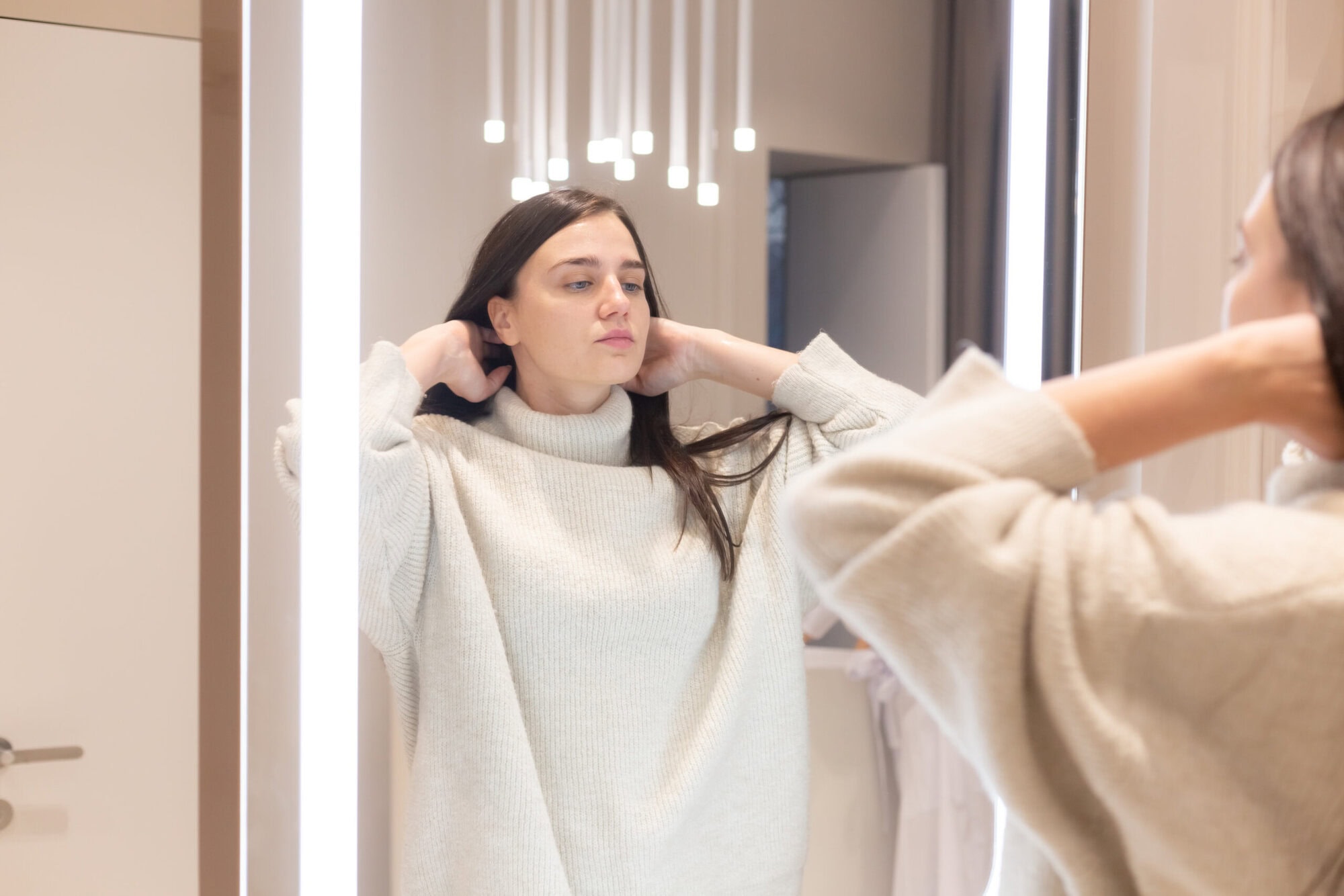 Woman looking at herself in the mirror pulling her hair