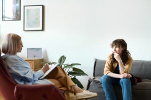 Woman sitting on couch talking to therapist who is taking notes