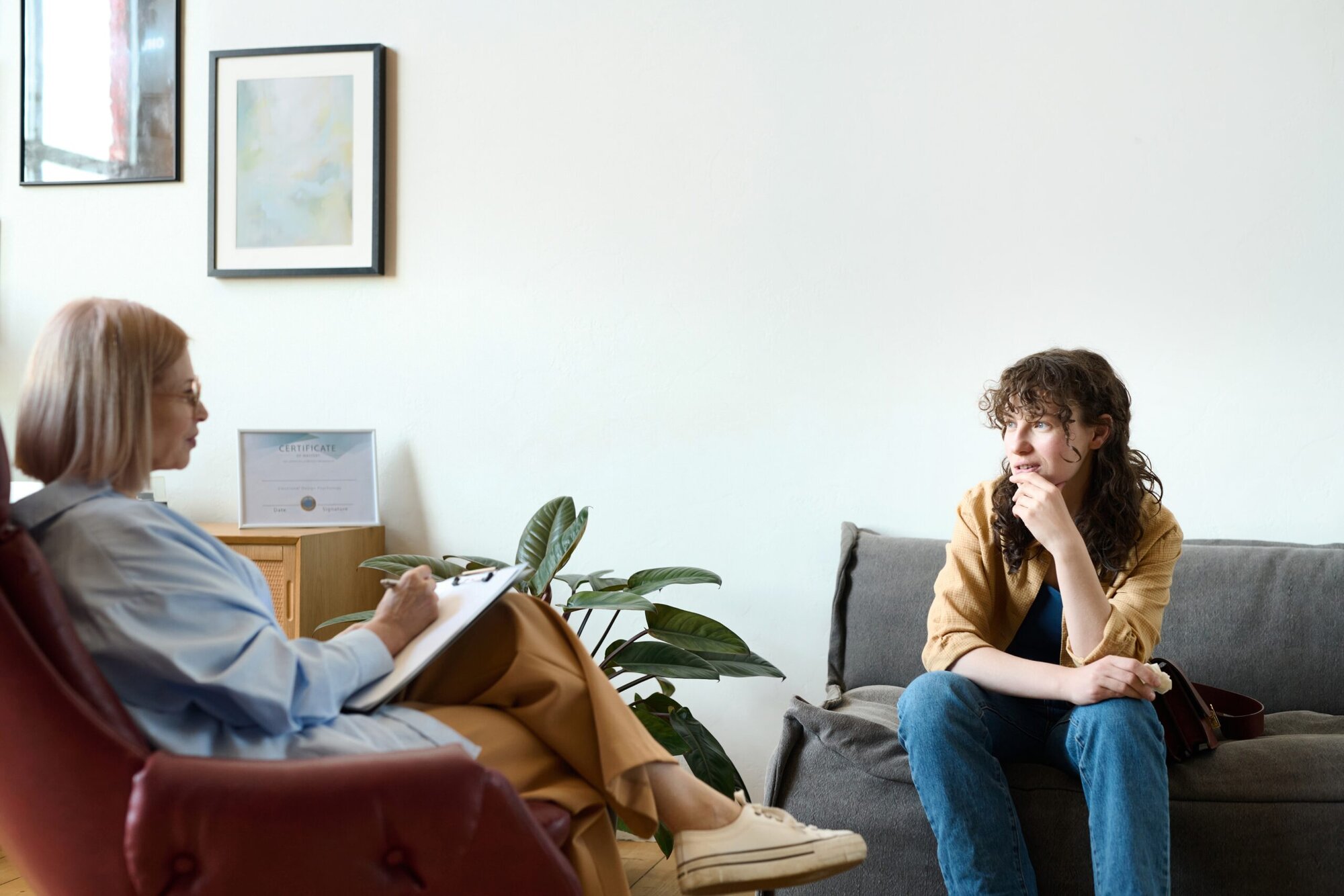 Woman sitting on couch talking to therapist who is taking notes