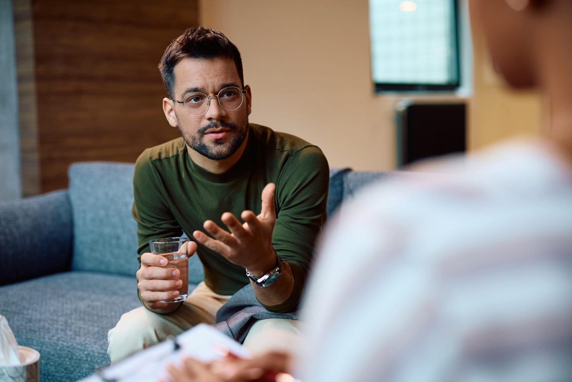 Man sitting on couch looking at therapist and talking.