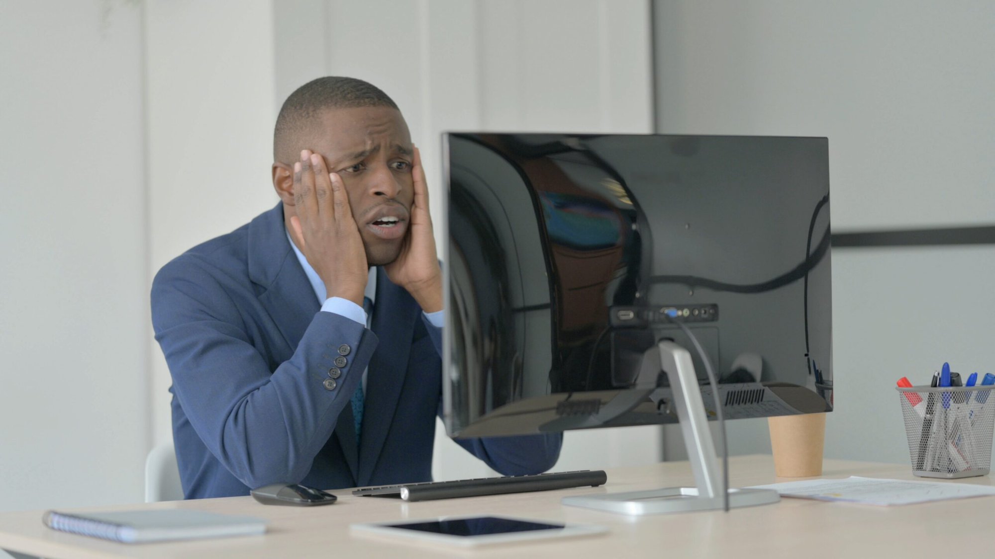 Man sitting at desk looking at computer screen. Looking frusrated.
