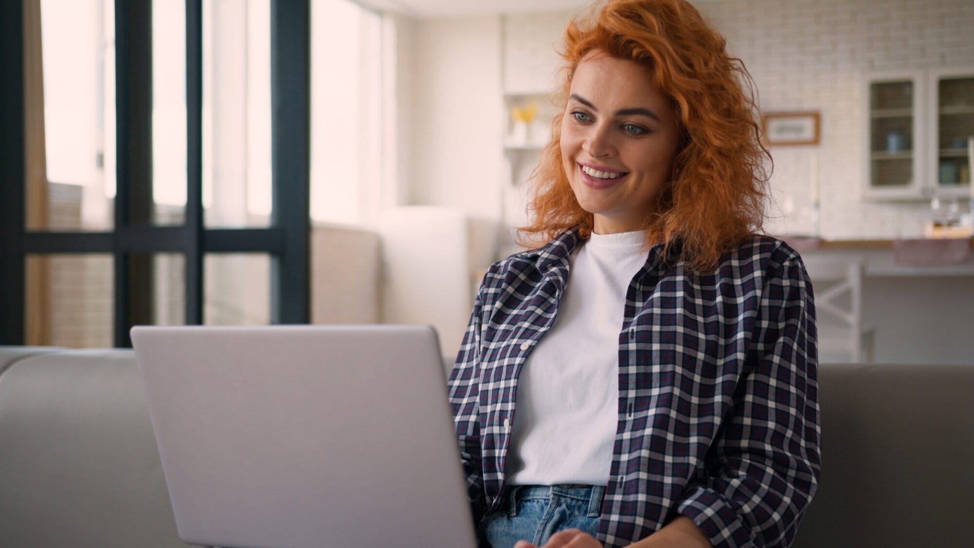 Woman sitting on couch talking to therapist on computer